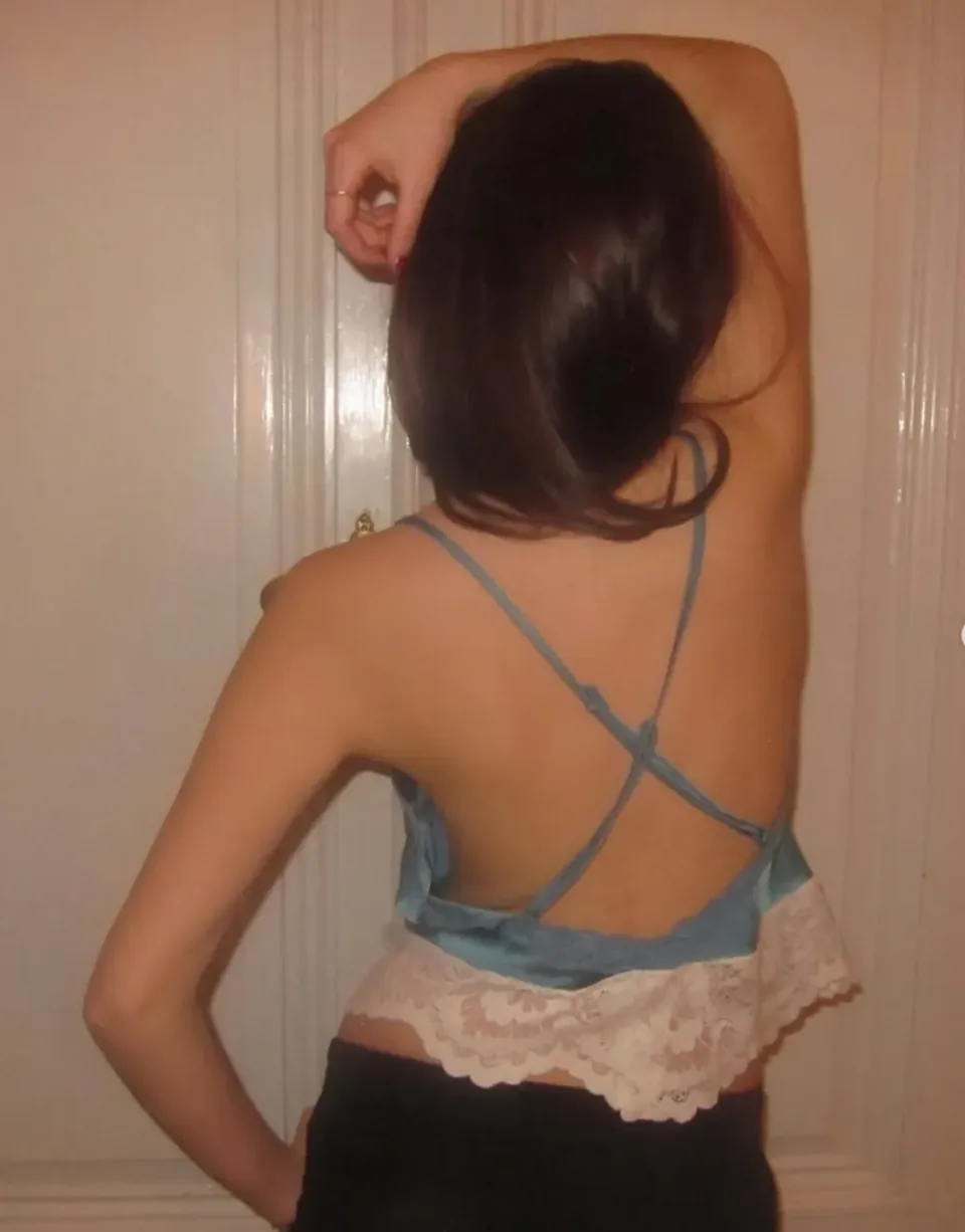 Back view of a pale blue camisole with lace trim and crossed straps across an otherwise bare back.